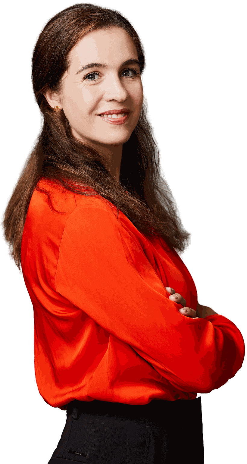 Sabine Karunanithy in an orange blouse, arms folded, smiling over her shoulder